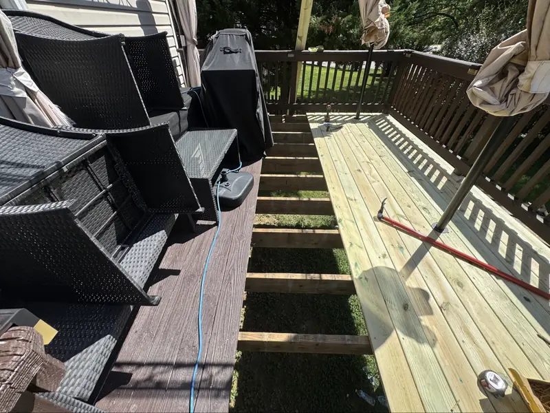 Deck re-decking in progress: worn dark boards on one side, new light boards going in on the other